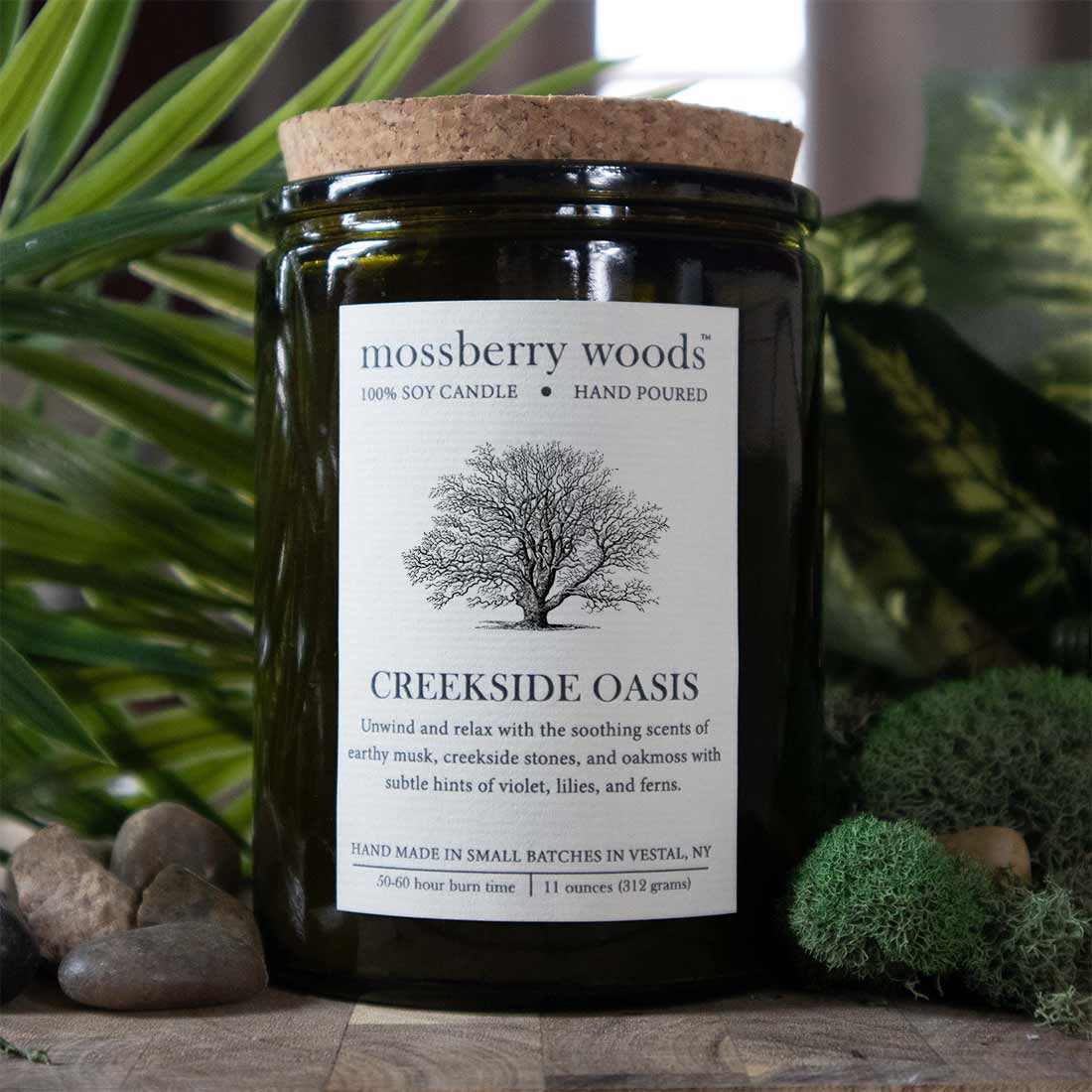 Creekside Oasis rustic soy candle in a vintage green container with fern, moss, and river stones in the background