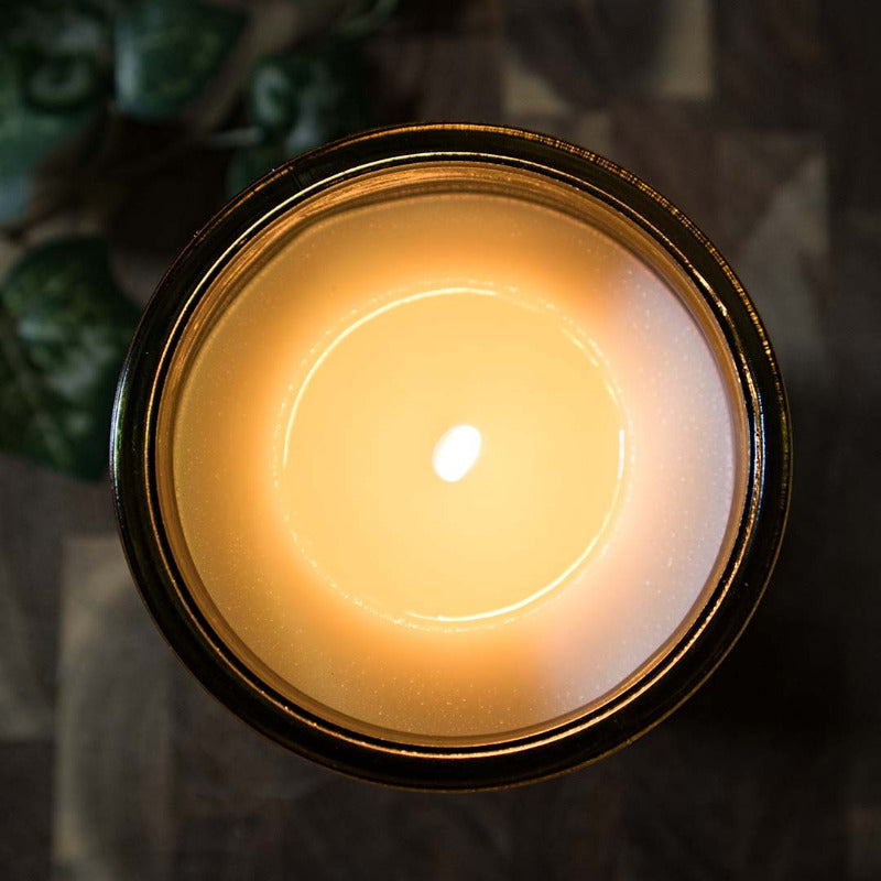 Top view of the lit amber glass candle showing the melt pool