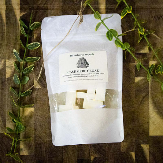 Cashmere Cedar wax melts sitting on a wood table with ivy branches