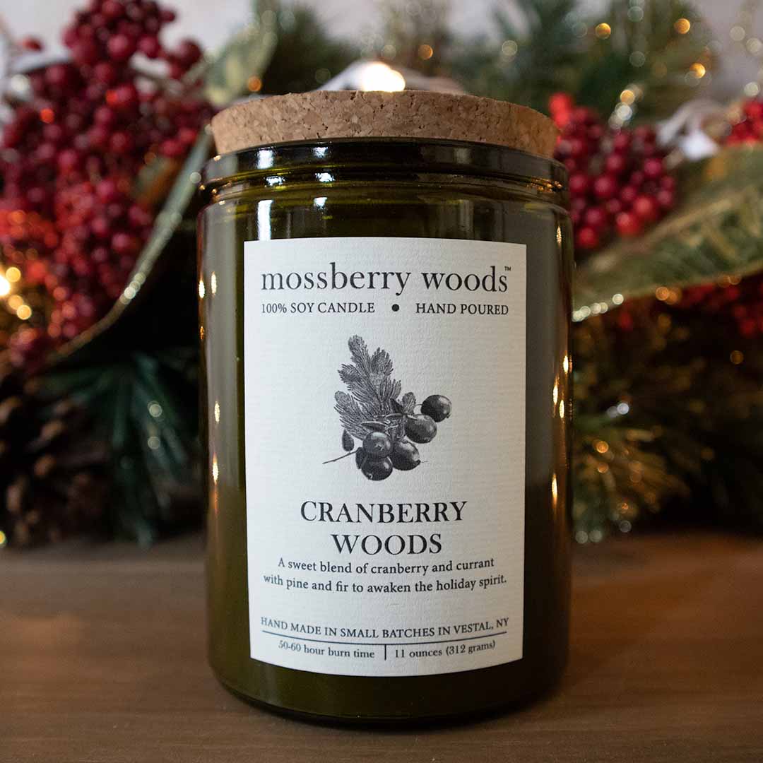 Cranberry Woods rustic candle on a wood table with cranberries in the background