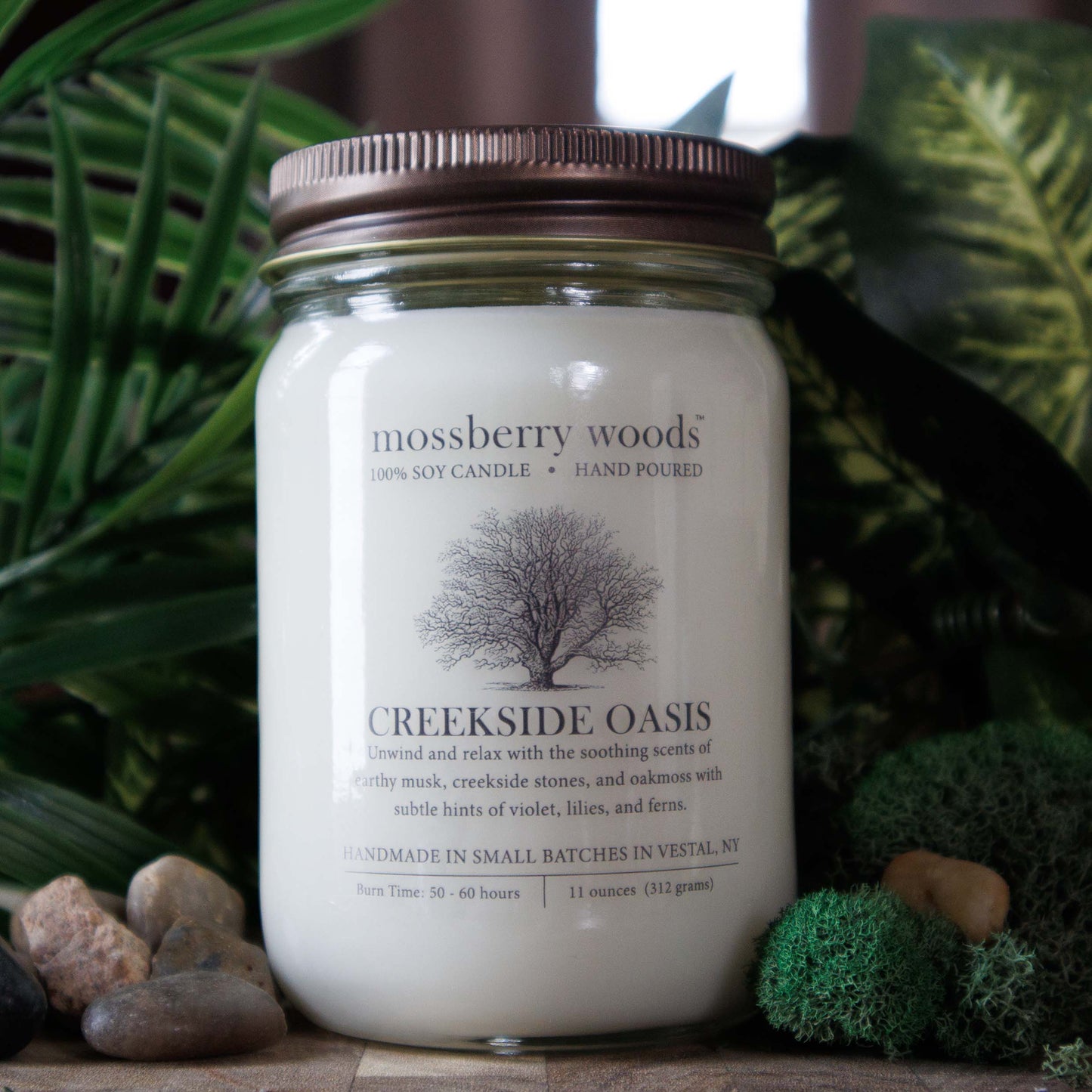 Creekside Oasis scented soy candle with ferns, moss, and stones.