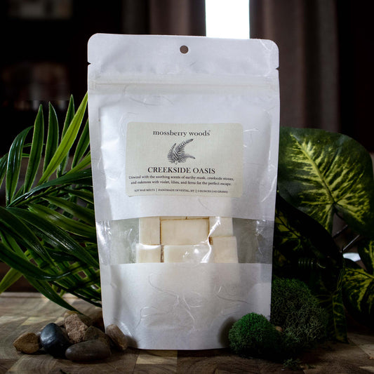 Creekside Oasis wax melts sitting on a wood table with fern and moss in the background