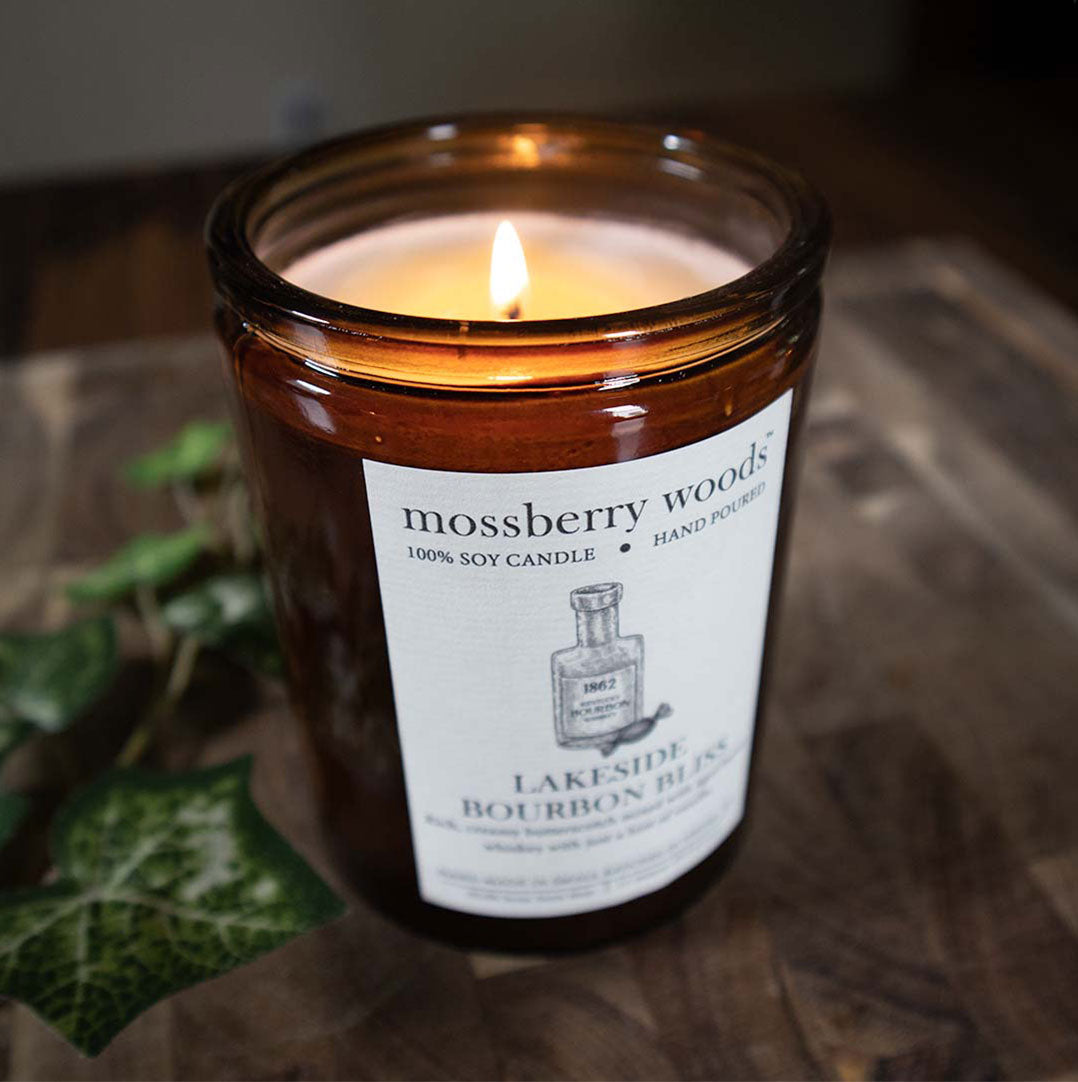 A lit Lakeside Bourbon Bliss rustic candle on a wooden table