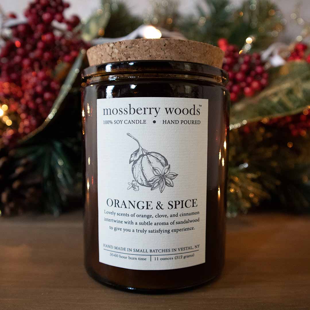 Orange & Spice rustic candle on a wood table with Christmas decorations in the background