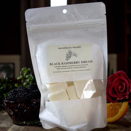 Black Raspberry Dream bag of wax melts with raspberries on a wood table