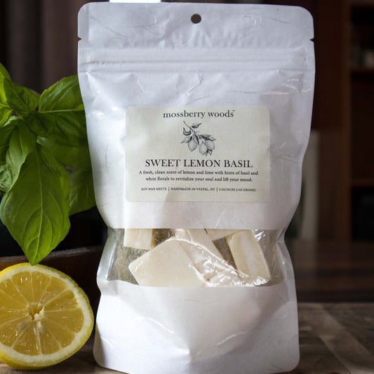 Lemon Basic wax melts sitting on a wood table with a lemon and a basil plant in the background