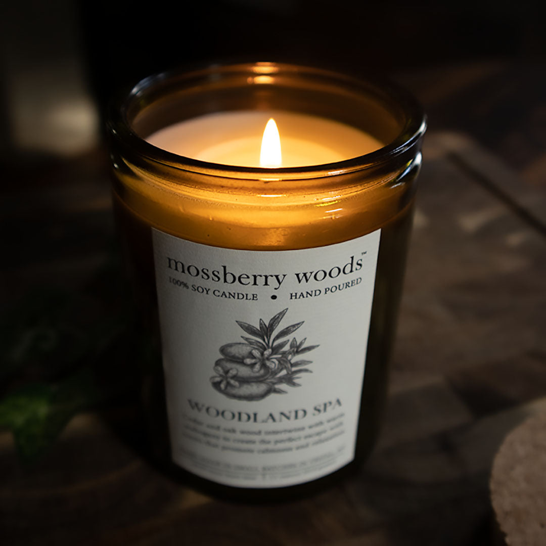 A lit soy candle with flame on a wooden block
